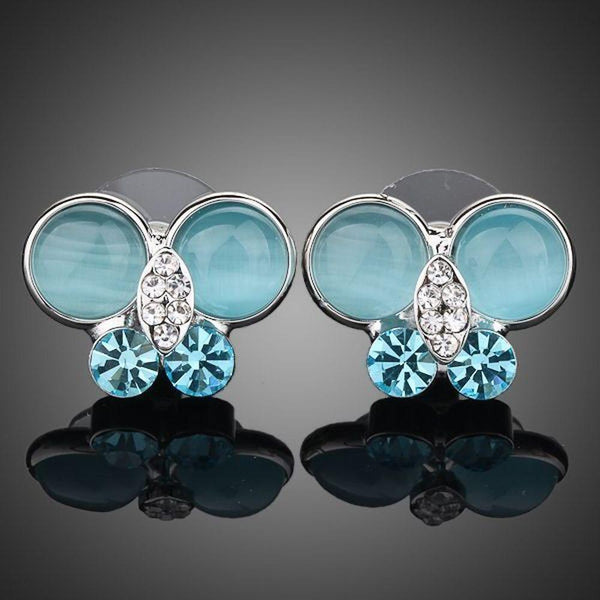 KHAISTA blue butterfly stud earrings on white background