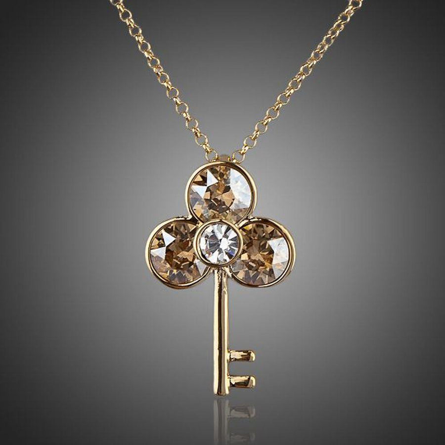 KHAISTA gold crystal key pendant necklace on white background