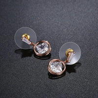 Side angle view of KHAISTA rose gold crystal drop earrings
