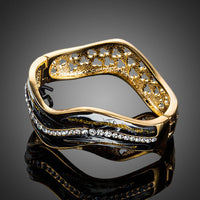 Side angle view of KHAISTA artistic black wave bangle