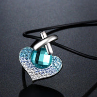 Side angle view of KHAISTA large blue Austrian crystal heart necklace