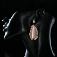 Side angle view of KHAISTA large opal waterdrop earrings