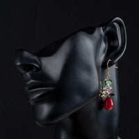 Side angle view of KHAISTA deep red crystal cluster drop earrings