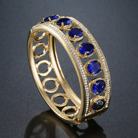 Close up detail of KHAISTA blue crystal gold bangle