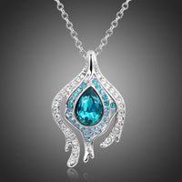 Side angle view of KHAISTA blue crystal pendant chain necklace