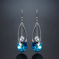 Close up of KHAISTA blue heart crystal drop earrings