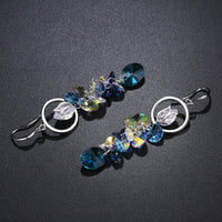 Close up of KHAISTA blue crystal long drop earrings
