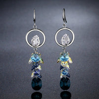 Side angle view of KHAISTA blue crystal long drop earrings