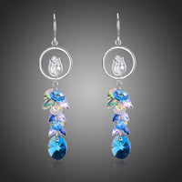 KHAISTA blue crystal long drop earrings on white background
