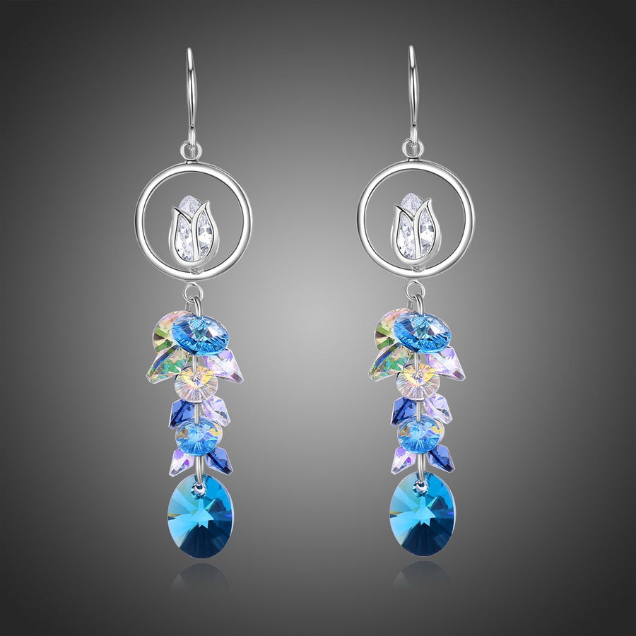 KHAISTA blue crystal long drop earrings on white background