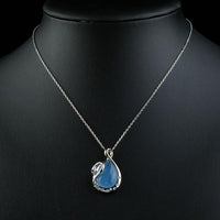 Side angle view of KHAISTA blue crystal swan pendant necklace