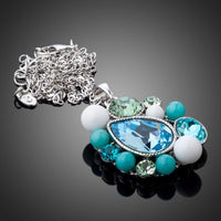 Side angle view of KHAISTA blue teardrop Stellux Austrian crystal necklace