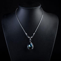 Side angle view of KHAISTA blue water crystal pendant necklace