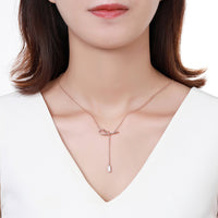 Side angle view of KHAISTA crystal bow knot pendant necklace