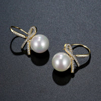 Side angle view of KHAISTA pearl bow knot dangle drop earrings