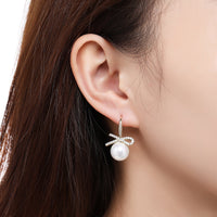 Close up of KHAISTA pearl bow knot dangle drop earrings