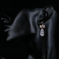 Side angle view of KHAISTA bow knot CZ drop earrings