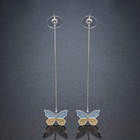 KHAISTA crystal butterfly drop earrings on white background