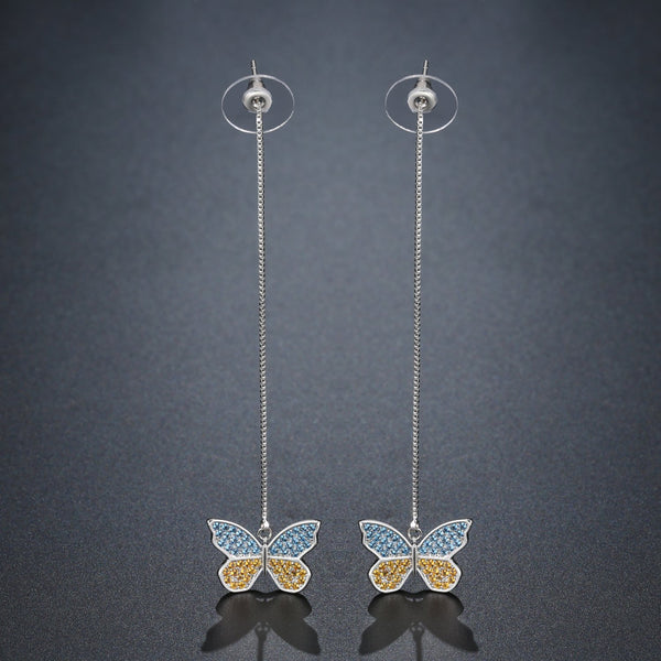 KHAISTA crystal butterfly drop earrings on white background