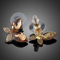 Side angle view of KHAISTA gold Stellux butterfly stud earrings