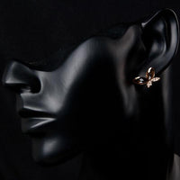 Close up of KHAISTA gold Stellux butterfly stud earrings