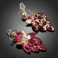 Close up of KHAISTA crystal butterfly raspberry drop earrings