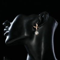 Side angle view of KHAISTA butterfly pearl drop earrings