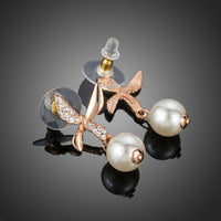 Close up of KHAISTA butterfly pearl drop earrings