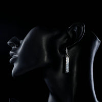 Side angle view of KHAISTA candle shape crystal drop earrings