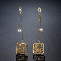 Close up of KHAISTA chain square pearl drop earrings