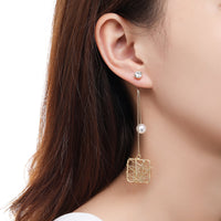 Side angle view of KHAISTA chain square pearl drop earrings