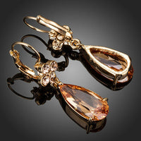Side angle view of KHAISTA champagne flower CZ hanging earrings