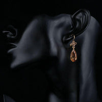 Close up of KHAISTA champagne flower CZ hanging earrings