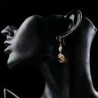 Side angle view of KHAISTA champagne round crystal drop earrings