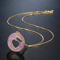 Side angle view of KHAISTA crown heart hollow round pendant necklace