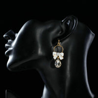 Side angle view of KHAISTA crystal bow knot drop earrings