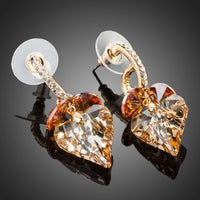 Close up of KHAISTA caramel crystal heart drop earrings