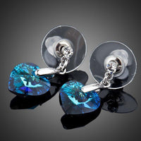 Close up of KHAISTA dark blue crystal heart drop earrings