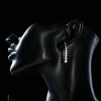 Side angle view of KHAISTA crystal steps drop earrings