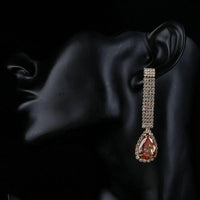 Side angle view of KHAISTA caramel CZ teardrop earrings
