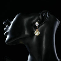 Side angle view of KHAISTA CZ pearl drop earrings