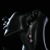 Close up of KHAISTA dangling heart crystal drop earrings
