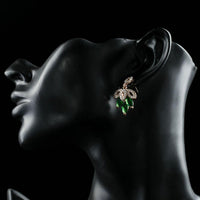 Side angle view of KHAISTA dark green leaves design drop earrings