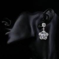 Side angle view of KHAISTA flower star CZ drop earrings