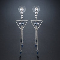 Close up of KHAISTA geometric blue crystal long drop earrings