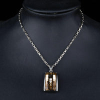 Side angle view of KHAISTA geometric champagne crystal pendant necklace