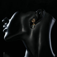 Side angle view of KHAISTA geometric crystal drop earrings