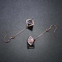 Side angle view of KHAISTA geometric hollow dangle earrings