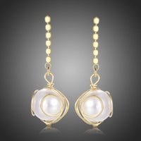 KHAISTA geometric pearl drop earrings on white background