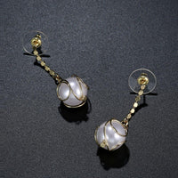 Side angle view of KHAISTA geometric pearl drop earrings